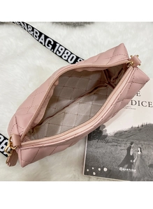 Detail view of pink quilted camera bag interior with logo-printed wide shoulder strap