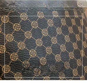 Close-up of brown textured synthetic leather with golden clover monogram pattern