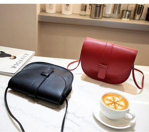 Detail of red and black PU leather saddle bags on a lifestyle marble tabletop