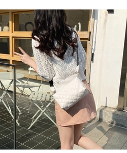 Gros plan du sac bandoulière blanc matelassé avec une large sangle tissée sur modèle
