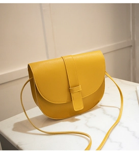 Detail view of ginger yellow PU leather saddle bag with flap closure and shoulder strap