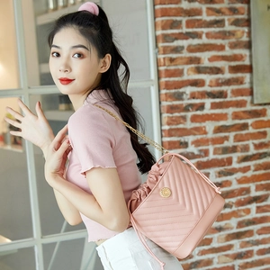 Close-up of pink quilted bucket bag with gold chain strap worn by a model