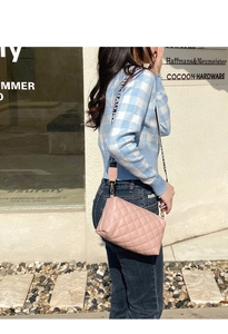 Close-up of pink quilted crossbody bag with stylish wide branded fabric shoulder strap
