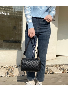 Gros plan sur un sac bandoulière matelassé noir avec une sangle tissée tendance