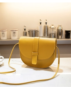 Detail of yellow saddle bag with PU leather texture and stylish magnetic flap closure