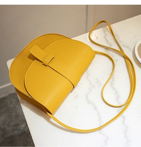 Detailed side view of a yellow saddle bag with clean stitching on white marble surface