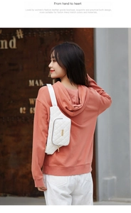 Outdoor shot of a white quilted waist bag with gold zipper and vertical metal detail