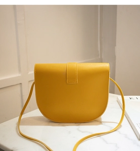 Detailed view of yellow PU saddle bag with lychee texture on marble surface