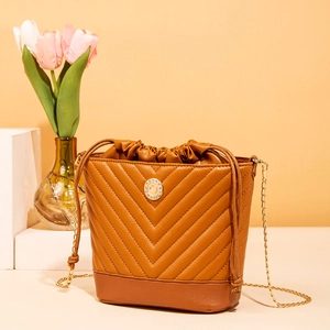 Macro detail of brown quilted bucket bag with V-shaped stitching and golden hardware