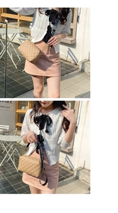 Gros plan sur un sac caméra matelassé beige avec sa bandoulière large à lettres stylées