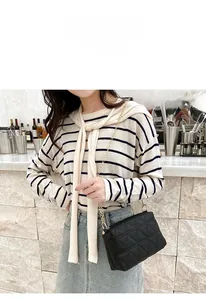 Close-up of black quilted shoulder bag with gold chain strap on a female model