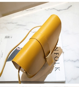 Detail of ginger yellow saddle bag with lychee grain texture and minimalist buckle strap