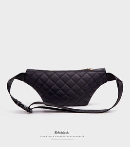 Close-up of black quilted waist bag with gold zipper and adjustable buckle strap
