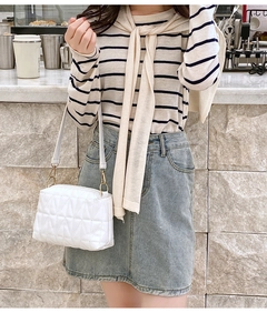 Detailed close-up of white quilted crossbody bag with gold hardware worn by a model