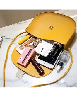 Internal storage view of yellow saddle bag with magnetic buckle on marble surface