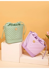 Close-up of quilted drawstring bucket bags in mint and lavender with gold chain straps