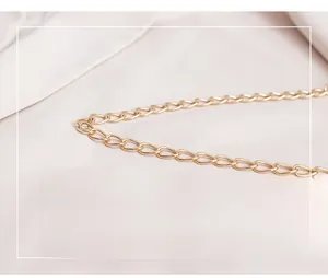 Macro shot of high-quality light gold metal chain strap on smooth beige fabric