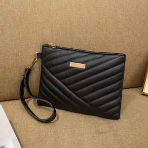 Elegant black quilted PU leather clutch bag with golden zipper and wristlet on sofa
