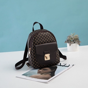Mini geometric patterned backpack with brown leather flap and gold buckle on blue background