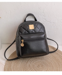 Macro shot of black quilted faux leather mini backpack with square golden metal hardware