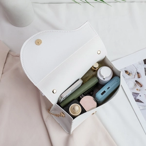 White saddle bag with gold clasp showing large interior storage and asymmetric flap design