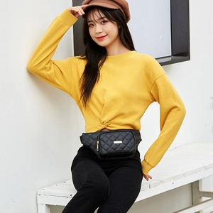 Classic black quilted fanny pack with gold metal zipper shown on model in outdoor setting