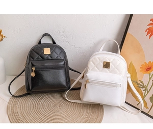 Detail of quilted leather mini backpacks in black and white with gold metal accents