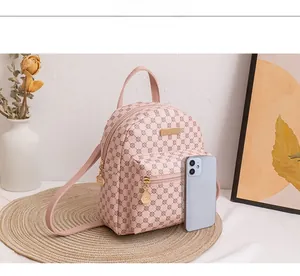 Detailansicht eines rosa Mini-Rucksacks mit Karomuster und Goldbeschlägen im Größenvergleich