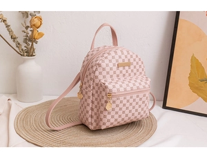 Detailansicht eines rosa Mini-Rucksacks mit Logomuster auf einer gewebten Matte