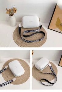 Three-angle views of white crossbody camera bag with wide letter-print strap and gold hardware