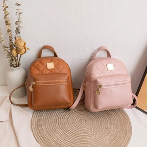 Quilted mini backpacks in brown and pink leather on a rustic woven mat backdrop