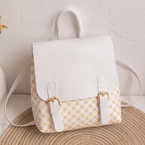 Detail of white leather knapsack with yellow circular prints and gold buckles on woven mat