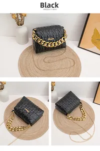 Detail view of black quilted faux leather crossbody bag with chunky gold chain accents