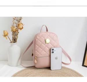 Pink quilted mini backpack with gold hardware shown next to a smartphone for scale