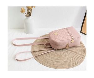 Close-up of pink quilted mini backpack with golden zipper on a straw mat background