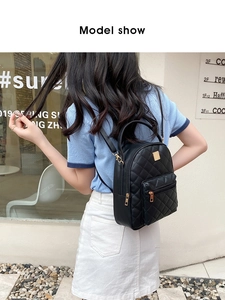 Fashionable black quilted backpack with gold metal logo and dual zippers on street model