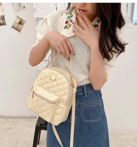 Detail of beige quilted mini backpack with diamond pattern and gold hardware