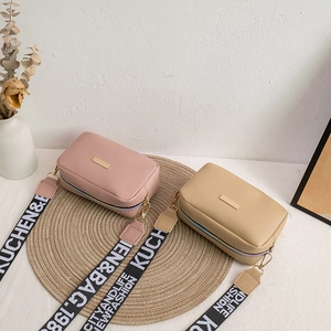 Minimalist leather crossbody camera bags in pink and apricot with wide woven straps