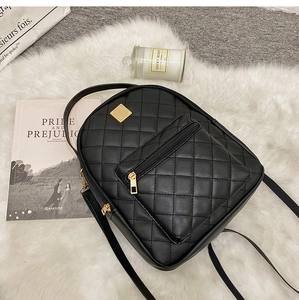 Detail of black quilted PU leather mini backpack with gold zippers on plush background