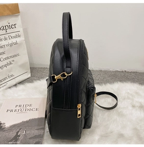 Side view of a black quilted leather backpack with gold zippers on a plush rug