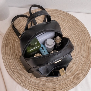 Black mini quilted backpack shown from top view with various everyday essentials inside