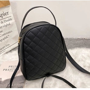 Detail of black mini PU leather backpack with classic diamond quilted pattern and metal zipper
