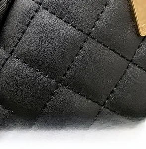 Macro detail of black quilted leather with fine texture and golden metal hardware