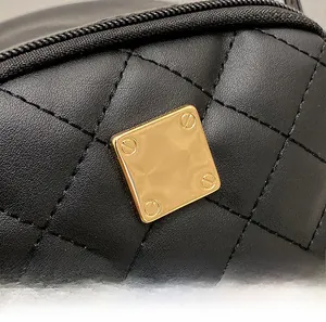 Macro shot of black quilted faux leather bag featuring a square gold hardware detail