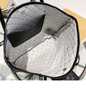 Interior detail of black quilted tote bag showing light grey lining and magnetic closure