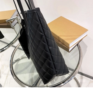 Detail view of quilted black tote bag with diamond stitching on glass table
