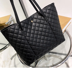 Close-up of quilted pattern on large black tote bag with gold hardware detail