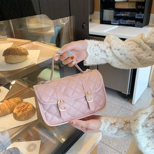 Pink quilted crossbody bag with golden buckles in a stylish bakery shop setting