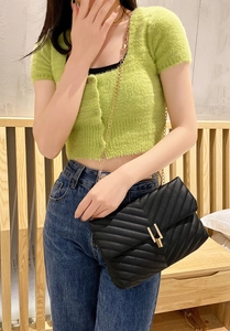 Détail du sac matelassé noir avec chaîne dorée et broderie élégante en V