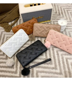 Detail of long embroidered wallets with fur pompom charms in five diverse colors